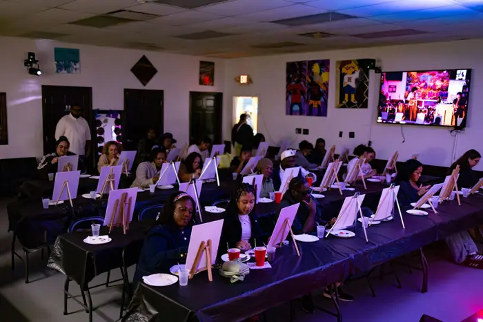 Full room of guests painting at long tables
