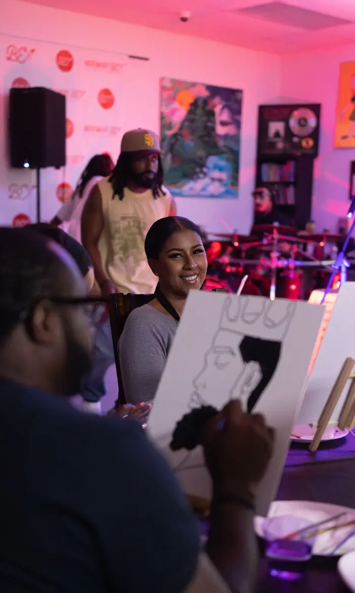 A guest holding up a finished canvas