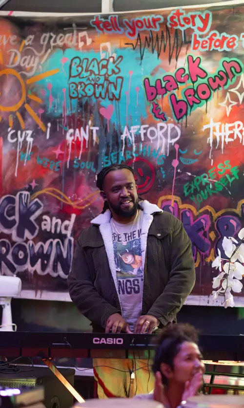 Host at the keys in front of the Black & Brown mural