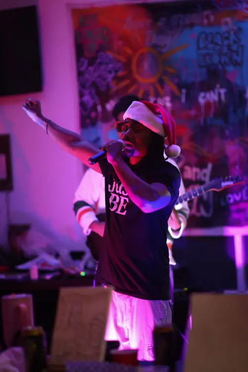 Vocalist in a Santa hat performing at the holiday edition